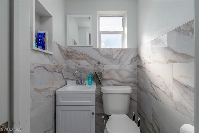 bathroom featuring vanity, toilet, and tile walls