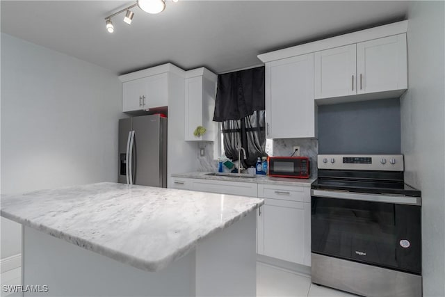 kitchen featuring a kitchen island, appliances with stainless steel finishes, sink, white cabinets, and light tile patterned floors