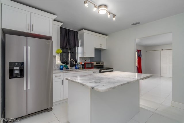 kitchen with appliances with stainless steel finishes, a barn door, sink, and white cabinets