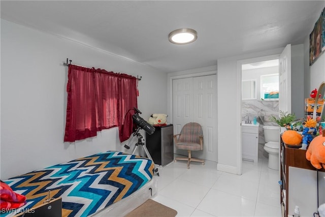 tiled bedroom featuring a closet and ensuite bathroom