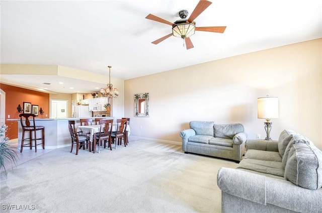 carpeted living room with ceiling fan with notable chandelier