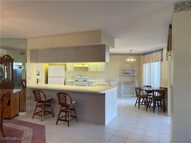 kitchen with sink, white appliances, light tile patterned flooring, decorative light fixtures, and kitchen peninsula