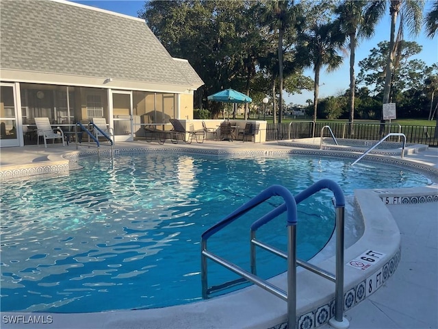 view of swimming pool with a sunroom and a patio area