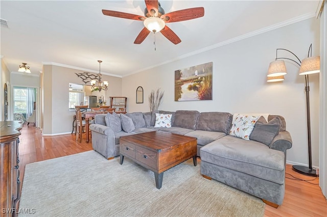 living room with crown molding, ceiling fan with notable chandelier, and light hardwood / wood-style floors