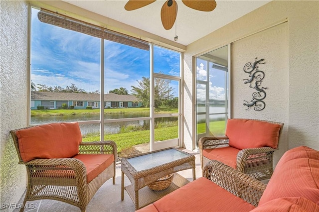 sunroom featuring ceiling fan and a water view