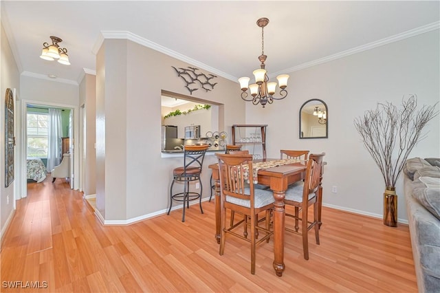 dining room with a notable chandelier, crown molding, and light hardwood / wood-style flooring