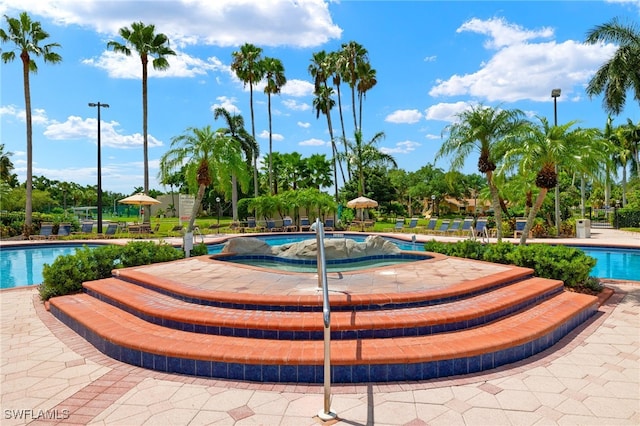 view of property's community featuring a pool with hot tub and a patio