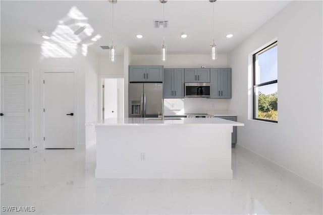 kitchen with sink, gray cabinetry, stainless steel appliances, a center island with sink, and decorative light fixtures