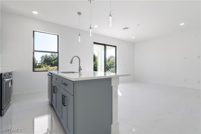 kitchen with sink, gray cabinetry, hanging light fixtures, appliances with stainless steel finishes, and a kitchen island with sink