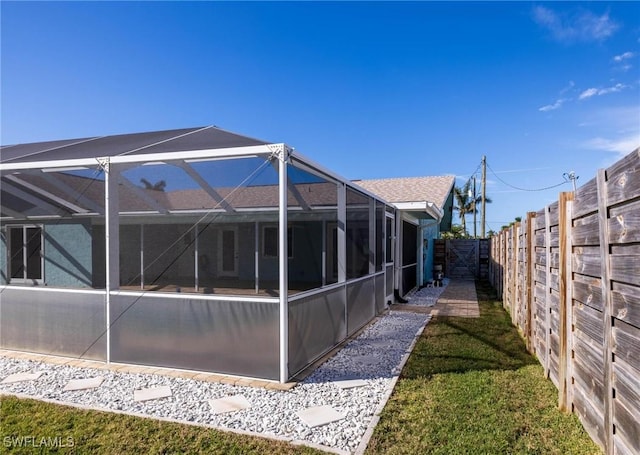 back of house with glass enclosure and a lawn