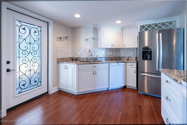 kitchen with sink, stainless steel fridge, dishwasher, light stone counters, and white cabinets