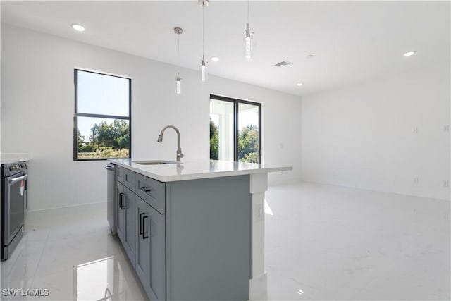 kitchen with appliances with stainless steel finishes, decorative light fixtures, sink, gray cabinetry, and a center island with sink