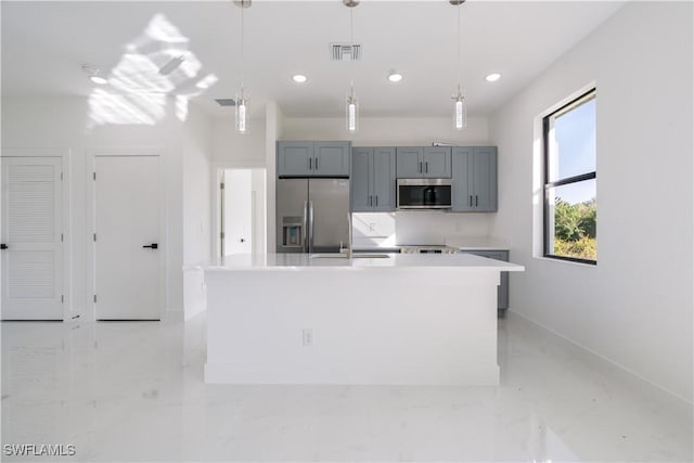 kitchen with sink, gray cabinetry, hanging light fixtures, stainless steel appliances, and a kitchen island with sink