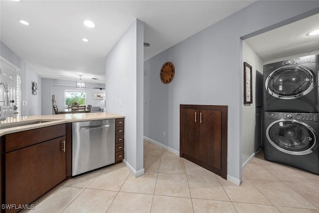 kitchen featuring light tile patterned flooring, dishwasher, sink, stacked washer and dryer, and dark brown cabinetry