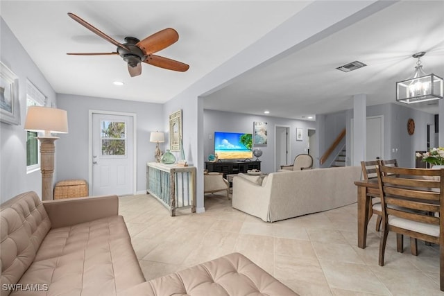 tiled living room featuring ceiling fan with notable chandelier