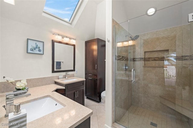 bathroom with tile patterned flooring, a skylight, vanity, an enclosed shower, and toilet