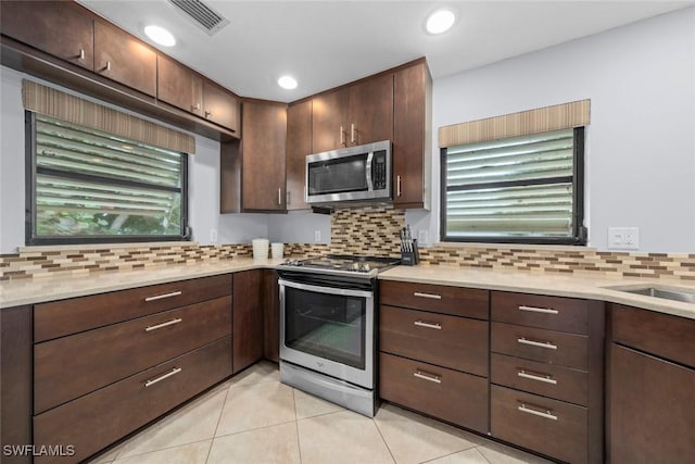 kitchen featuring light tile patterned floors, sink, stainless steel appliances, dark brown cabinetry, and decorative backsplash