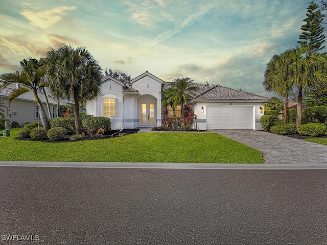 mediterranean / spanish-style house with a garage and a lawn