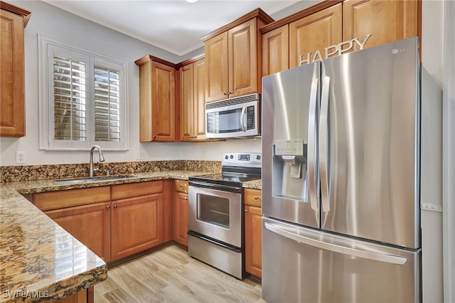 kitchen featuring stainless steel appliances, sink, stone counters, and light wood-type flooring