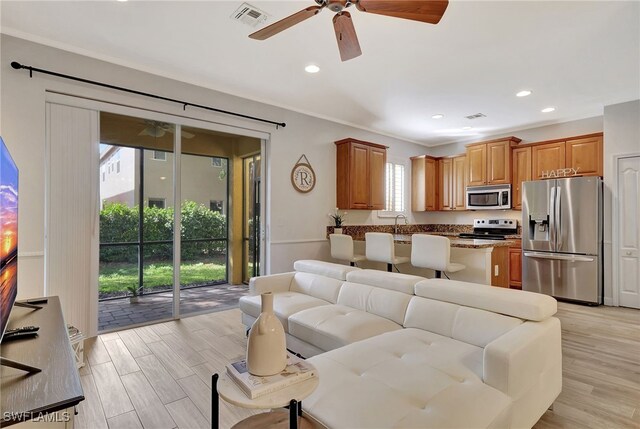 living room with crown molding, ceiling fan, and light hardwood / wood-style floors