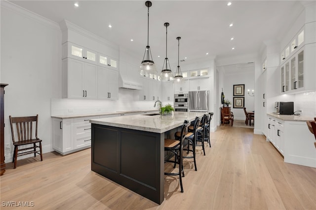 kitchen with sink, white cabinetry, hanging light fixtures, a large island, and light stone countertops