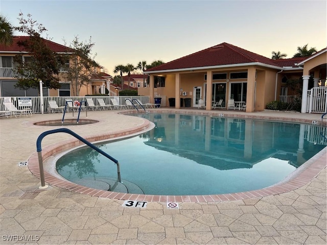 pool at dusk with a patio area