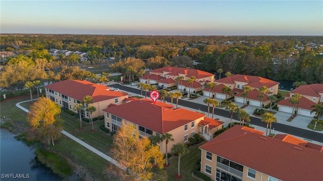 aerial view at dusk featuring a water view