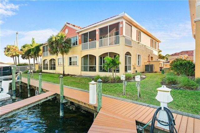 dock area featuring cooling unit, a lawn, and a water view