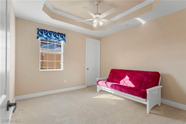 sitting room featuring ceiling fan, ornamental molding, a tray ceiling, and carpet floors