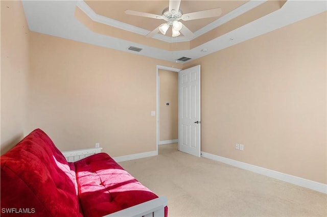 sitting room featuring crown molding, a tray ceiling, light colored carpet, and ceiling fan