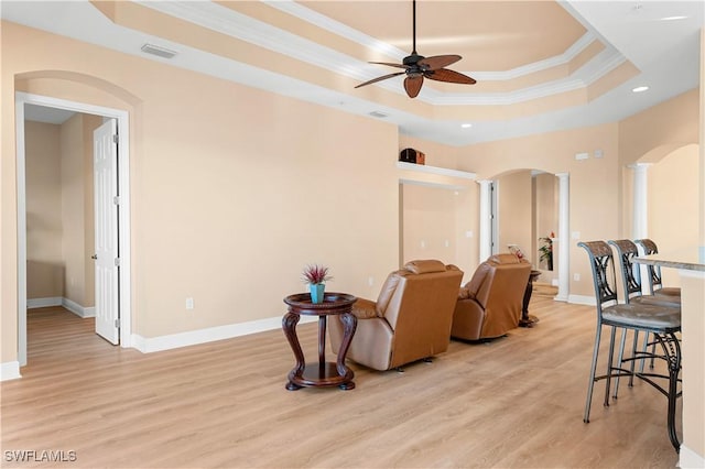 interior space with decorative columns, crown molding, light hardwood / wood-style flooring, and a tray ceiling