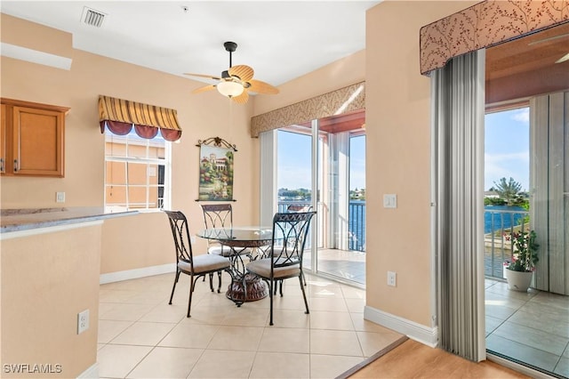 tiled dining room featuring a water view and ceiling fan