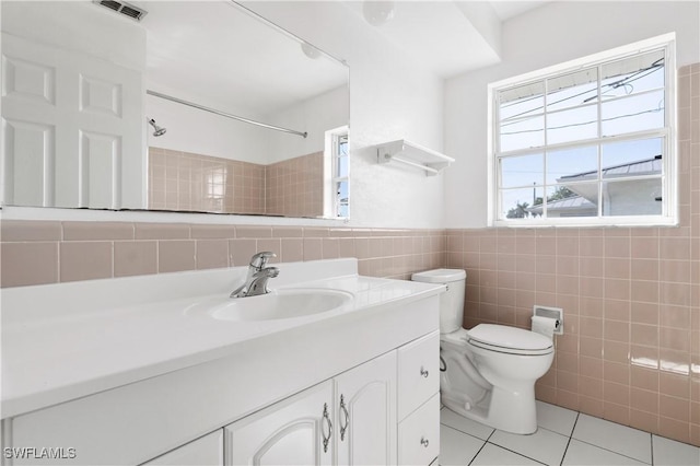 bathroom with tile walls, vanity, walk in shower, toilet, and tile patterned floors