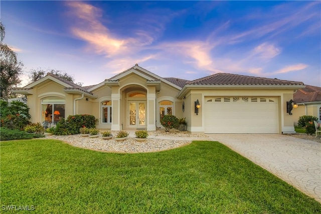 mediterranean / spanish-style home with a garage and a yard