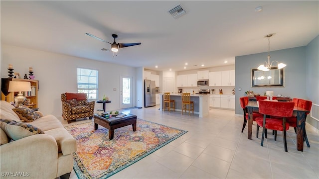 tiled living room featuring ceiling fan with notable chandelier