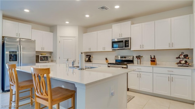 kitchen featuring white cabinetry, appliances with stainless steel finishes, a kitchen island with sink, and a kitchen breakfast bar