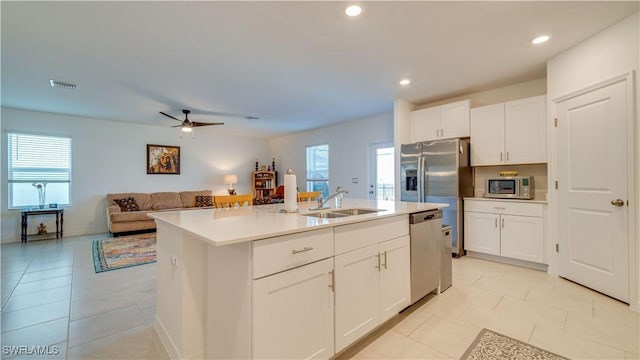 kitchen featuring an island with sink, white cabinetry, sink, light tile patterned floors, and stainless steel appliances