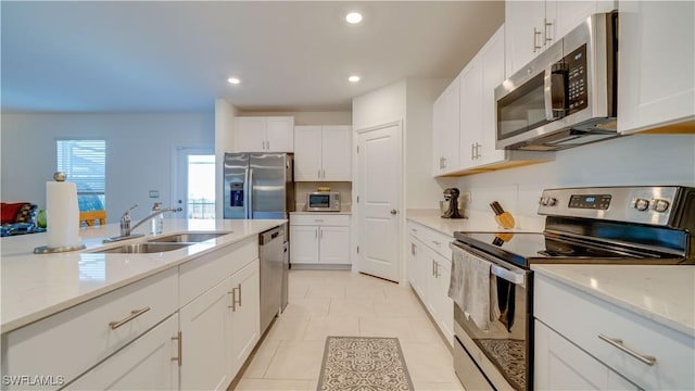 kitchen with white cabinetry, appliances with stainless steel finishes, sink, and light stone counters