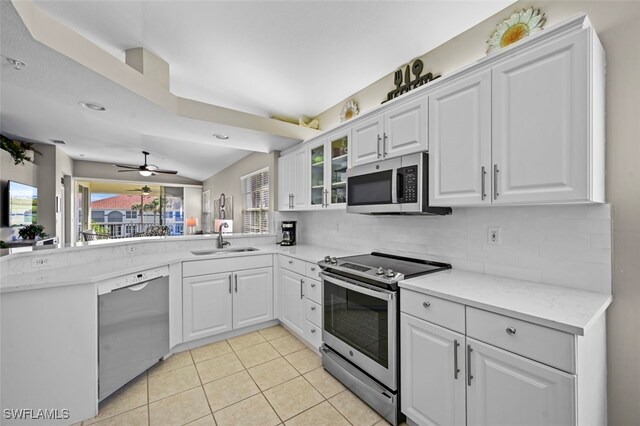 kitchen featuring sink, appliances with stainless steel finishes, kitchen peninsula, decorative backsplash, and white cabinets