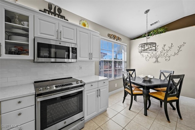 kitchen with white cabinetry, lofted ceiling, backsplash, hanging light fixtures, and stainless steel appliances