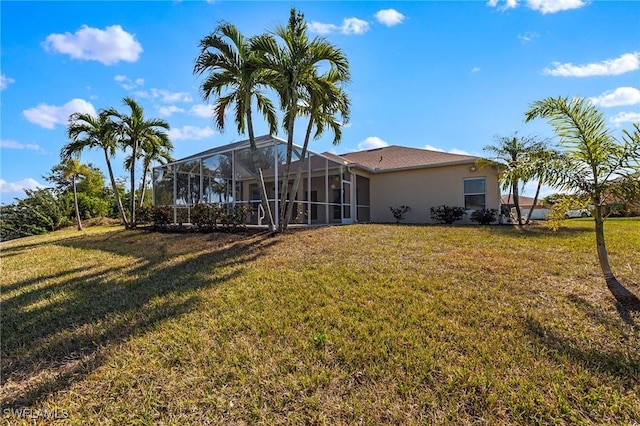 back of house with a yard and a lanai