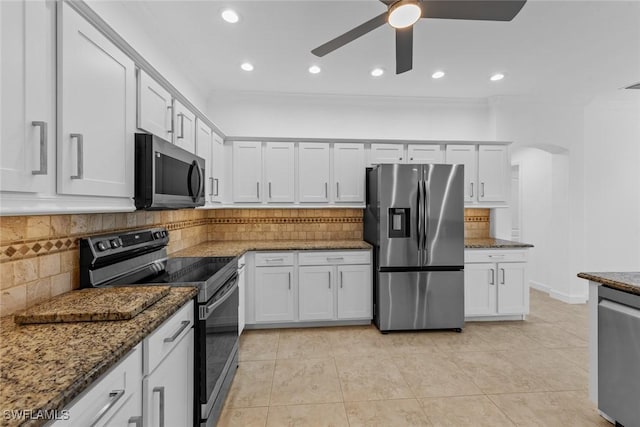 kitchen with white cabinetry, appliances with stainless steel finishes, dark stone countertops, and decorative backsplash