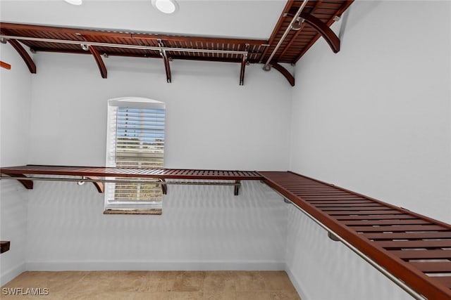 walk in closet featuring beamed ceiling and light tile patterned floors