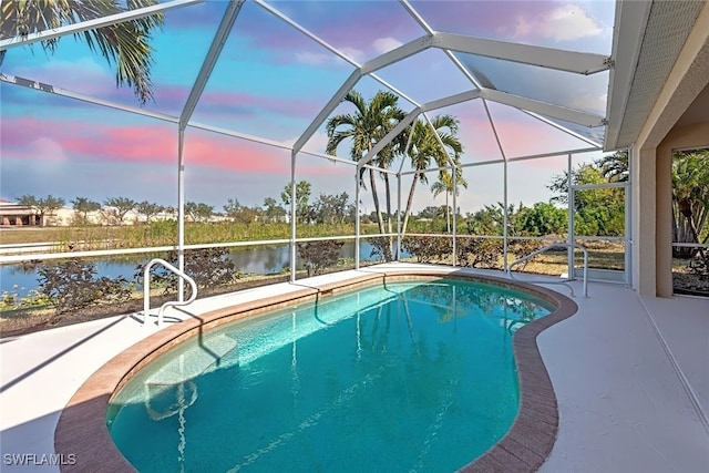 pool at dusk with a water view, a lanai, and a patio area