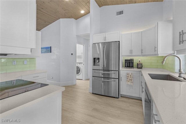 kitchen with appliances with stainless steel finishes, washer / dryer, sink, white cabinets, and wood ceiling