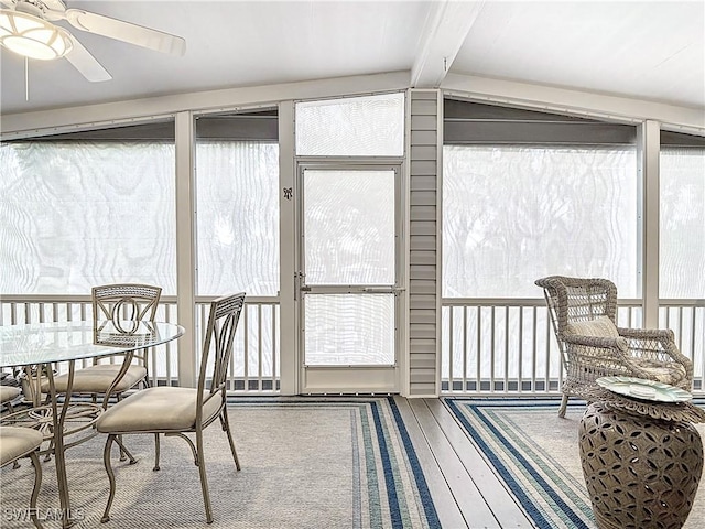 sunroom / solarium featuring ceiling fan, plenty of natural light, and lofted ceiling with beams