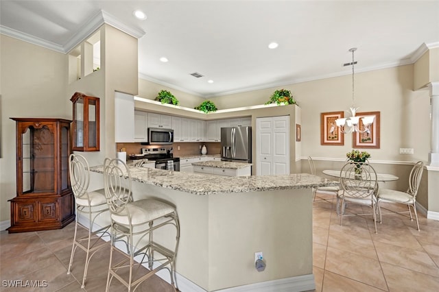 kitchen with decorative light fixtures, light tile patterned floors, ornamental molding, appliances with stainless steel finishes, and kitchen peninsula