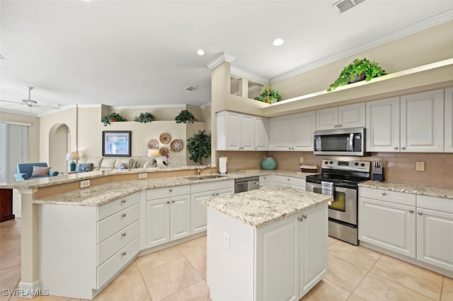 kitchen featuring appliances with stainless steel finishes, white cabinetry, sink, a center island, and crown molding