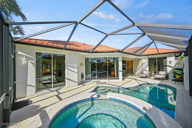 rear view of property featuring a swimming pool with hot tub, a patio area, and glass enclosure