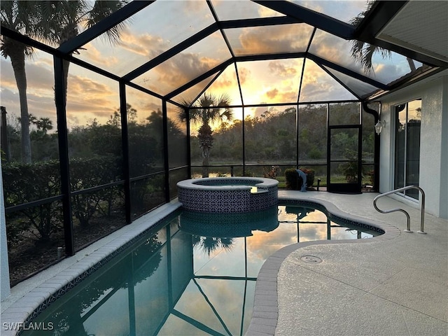 pool at dusk with an in ground hot tub, glass enclosure, and a patio